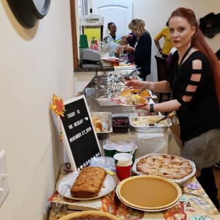 A group of people enjoying a potluck with a variety of desserts and dishes laid out on a table.