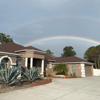 A suburban house with a striking double rainbow arcing across the sky.