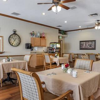 A cozy dining room with neatly set tables and warm lighting.