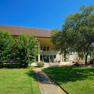 A spacious house with a large lawn and trees under a clear blue sky.