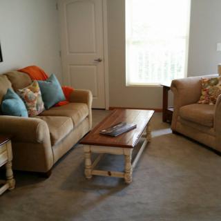A cozy living room featuring a sofa, armchair, and wooden coffee table with decorative pillows.