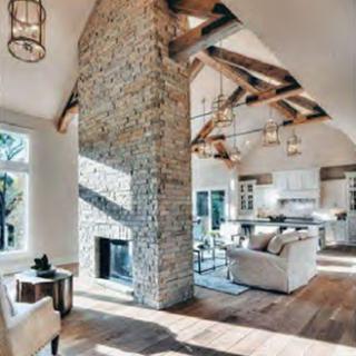 A beautifully designed modern living room featuring a stone fireplace and wooden beams, creating a warm and inviting atmosphere.