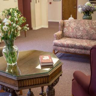 A cozy living room with a sofa, table, and flowers in a vase.