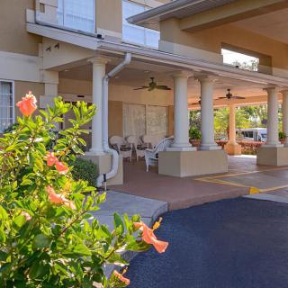 Hotel entrance with a covered patio and blooming flowers.