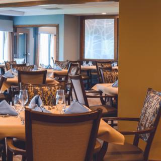 An elegant and empty dining room set with tables and chairs, ready for guests.