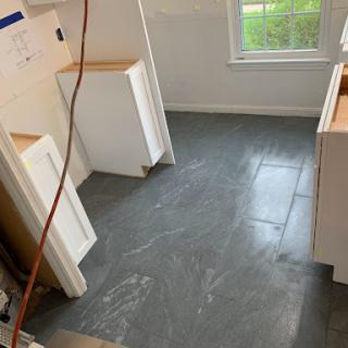 A newly tiled kitchen floor during renovation, showcasing the modern grey slate tiles.