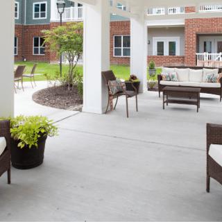 A well-furnished outdoor patio area in an apartment complex, featuring comfortable seating and surrounding landscaping.