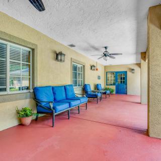 A spacious covered patio with blue cushioned seating and ceiling fans.