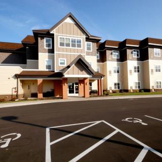 A modern residential building with a spacious parking lot in front.