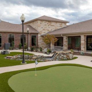 A residential building with a landscaped outdoor area featuring a putting green.