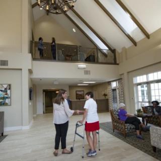 A spacious lobby with high ceilings, featuring people engaged in conversation and enjoying the well-lit area.