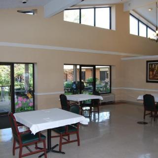 A well-lit dining area with tables and chairs, featuring large windows that let in natural light.