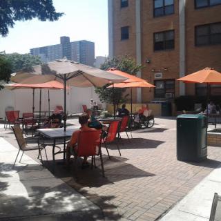 A sunny outdoor patio area with orange umbrellas and chairs, perfect for socializing.