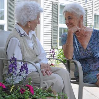 Two elderly women enjoying a conversation in the garden.