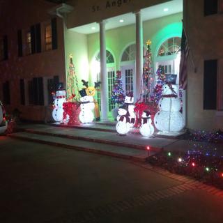 Festive Christmas decorations with lights and snowmen adorn the entrance at night.