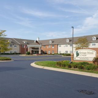 A large building with a driveway and well-maintained landscaping under a partly cloudy sky.