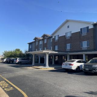 A hotel building with a parking lot under a clear blue sky.