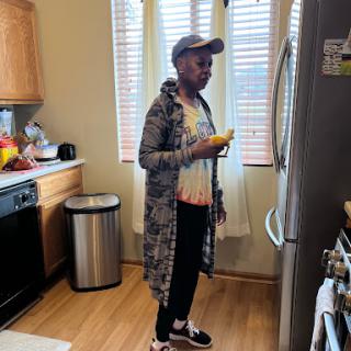 A woman standing in her kitchen, holding a yellow item while looking at the fridge.
