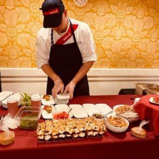 A chef preparing sushi at a buffet setup.
