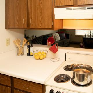 A cozy kitchen with a pot on the stove, lemons in a bowl, and utensils in a holder.