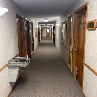 A long hallway featuring multiple doors and a water fountain.