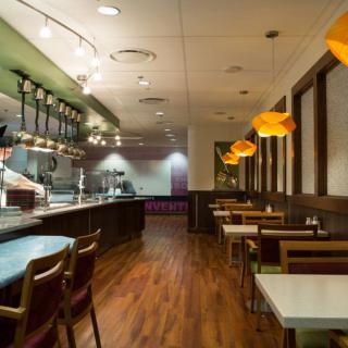 A modern restaurant interior with a view of the dining area and open kitchen.
