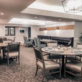 A modern dining area with neatly arranged tables and chairs, featuring elegant lighting and decor.