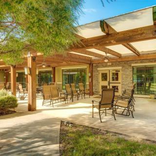 A spacious patio with outdoor furniture under a wooden pergola on a sunny day.