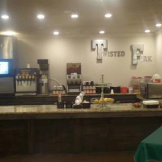 A restaurant counter with a beverage station and various food items displayed.