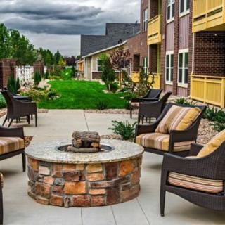 Outdoor patio area with a fire pit and seating at an apartment complex.
