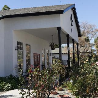 A charming white house with a covered porch and surrounding garden.