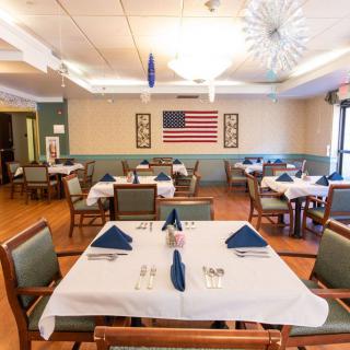 A dining area with neatly arranged tables and chairs, decorated with an American flag on the wall.
