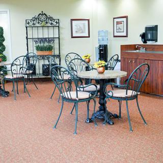 A cozy waiting area with metal chairs and tables, featuring a reception desk in the background.
