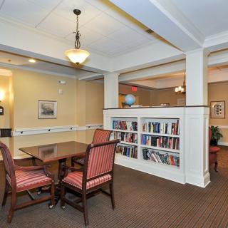 A cozy library space with a table and chairs for studying, surrounded by bookshelves.