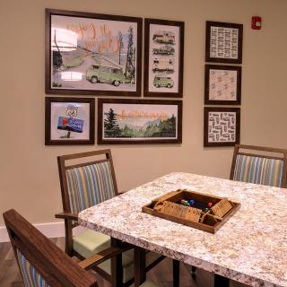 A cozy dining area with a game set on the table and framed artwork on the wall.