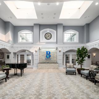 A spacious and elegant lobby with a grand piano, ample seating, and large skylights.