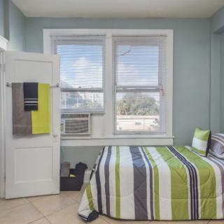 A minimalist bedroom with striped bedding and a window featuring an air conditioner.