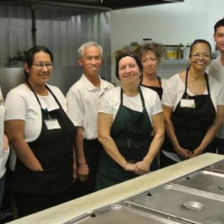 A group of people working together in a kitchen, wearing uniforms.