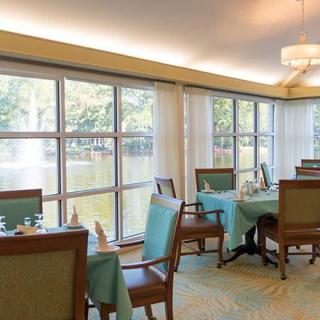 A well-lit dining area with multiple tables and chairs, set near large windows overlooking a scenic view.