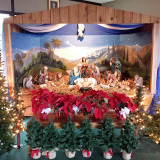 A beautifully arranged nativity scene adorned with poinsettias and festive lights, capturing the spirit of Christmas.