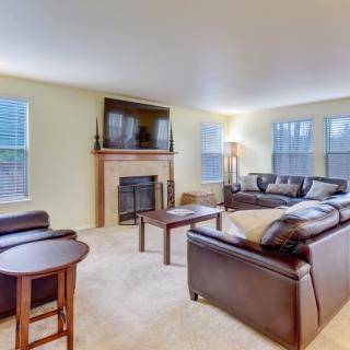 A cozy living room with a seating area, fireplace, and large windows.