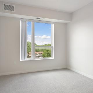 A minimalist empty room with a large window and white walls.