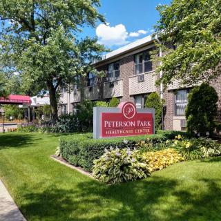 An apartment complex with a sign for Peterson Park, surrounded by trees and well-maintained landscaping.