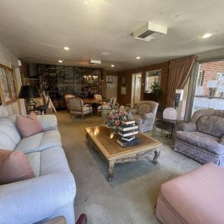 A cozy living room with comfortable seating and a central coffee table, surrounded by bookshelves and natural lighting.