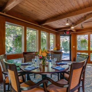 A cozy dining area with wooden interiors and large windows letting in natural light.