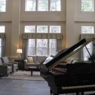 A spacious living room with high ceilings and a grand piano.
