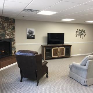 A modern living room featuring a television, fireplace, and cozy armchairs.