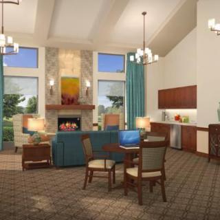 A modern living room with a fireplace and dining table, featuring elegant chandeliers and large windows.