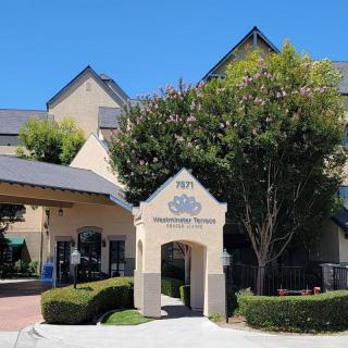 The exterior view of a hotel entrance surrounded by trees.