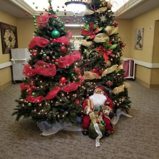A festive display featuring beautifully decorated Christmas trees and a decorative doll, creating a joyful holiday atmosphere.